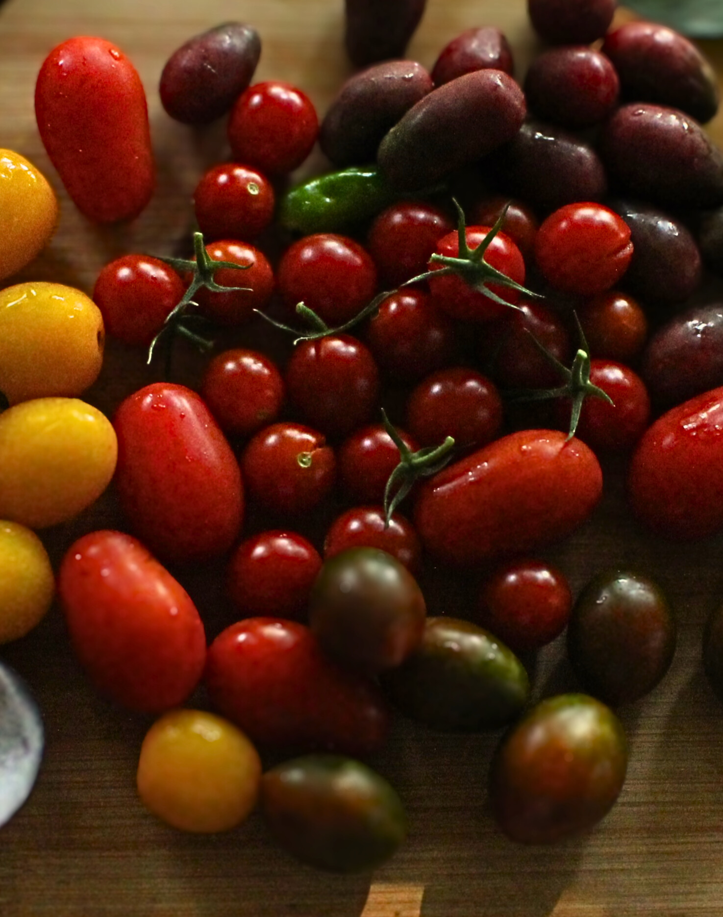 Close-up of cherry tomatoes mid-prep on a wooden cutting board in Paula Naumcheff’s kitchen.